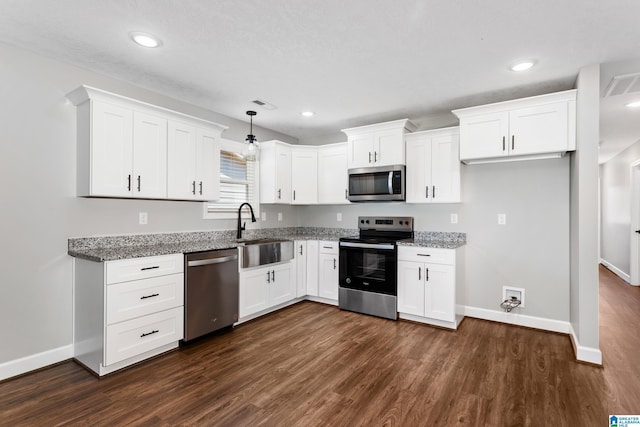 kitchen with light stone countertops, a sink, stainless steel appliances, baseboards, and dark wood-style floors
