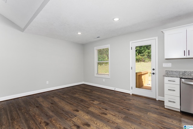 unfurnished dining area featuring vaulted ceiling, dark hardwood / wood-style flooring, and a textured ceiling