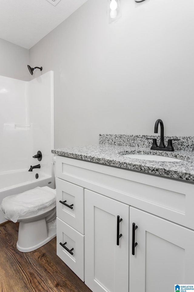 full bathroom with wood-type flooring, toilet, shower / washtub combination, and vanity