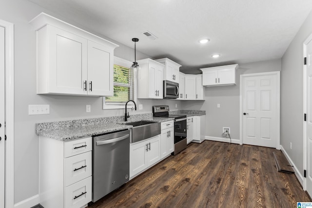 kitchen with decorative light fixtures, light stone counters, stainless steel appliances, and white cabinetry