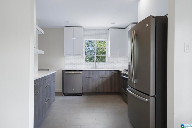 kitchen with backsplash, sink, appliances with stainless steel finishes, and white cabinets