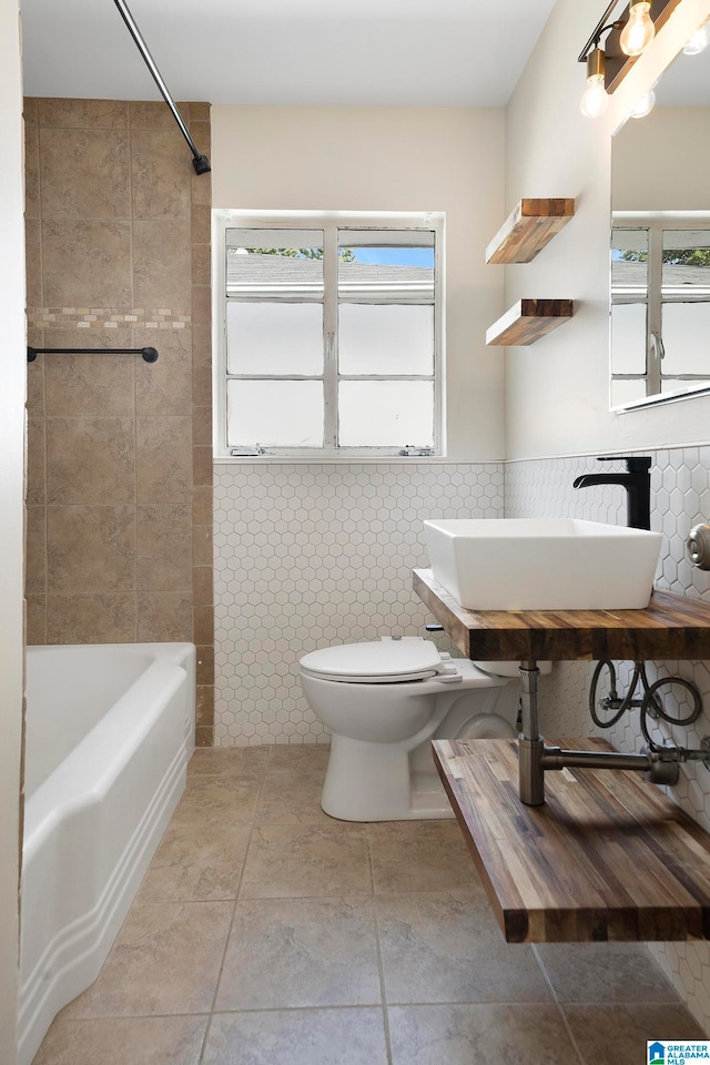 full bathroom with tile walls, toilet, a healthy amount of sunlight, and sink