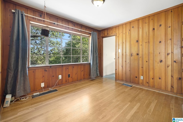 spare room featuring wood walls and light wood-type flooring