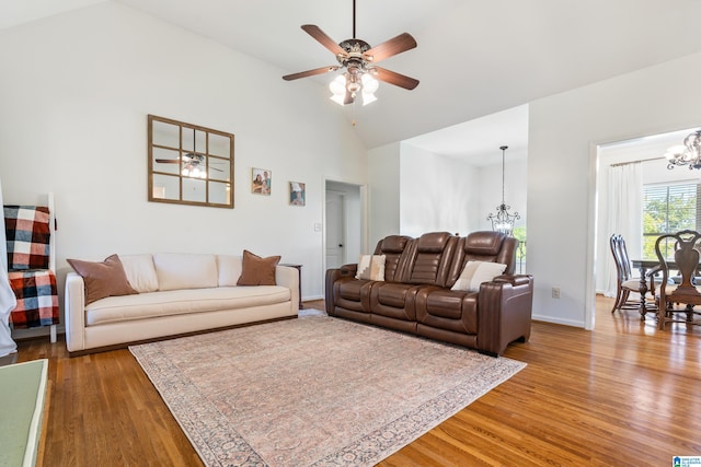 living room with high vaulted ceiling, ceiling fan with notable chandelier, and light hardwood / wood-style flooring