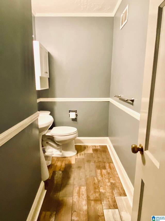 bathroom featuring crown molding, toilet, and hardwood / wood-style flooring