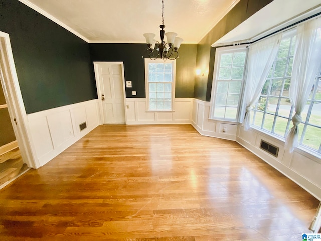 unfurnished dining area with crown molding, light hardwood / wood-style floors, and a notable chandelier