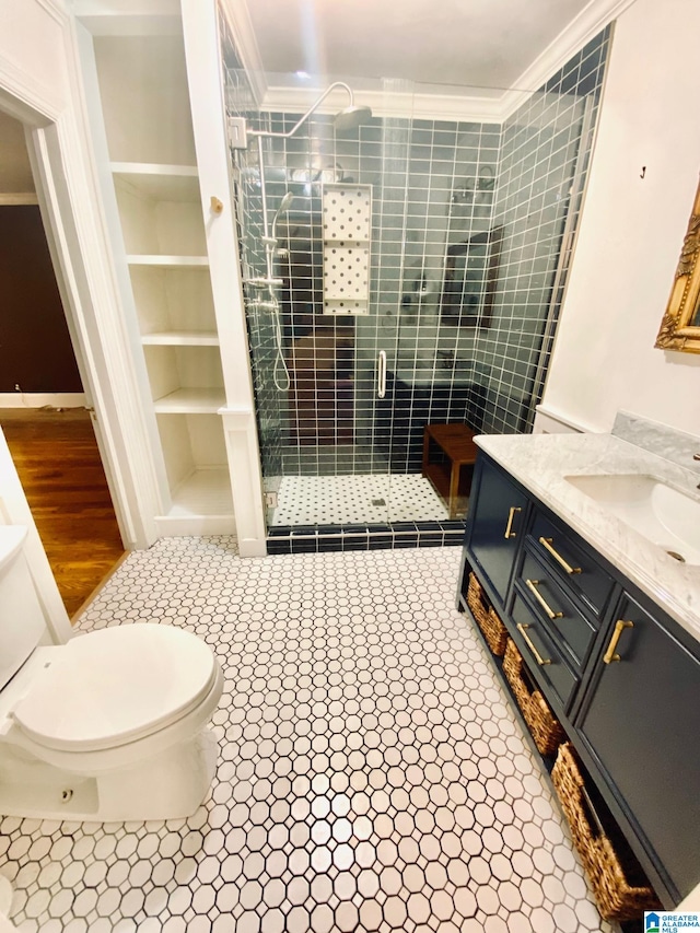 bathroom with vanity, a shower with shower door, tile patterned flooring, toilet, and ornamental molding