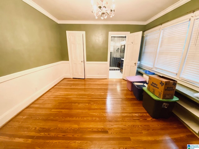 interior space featuring wood-type flooring, a chandelier, and ornamental molding