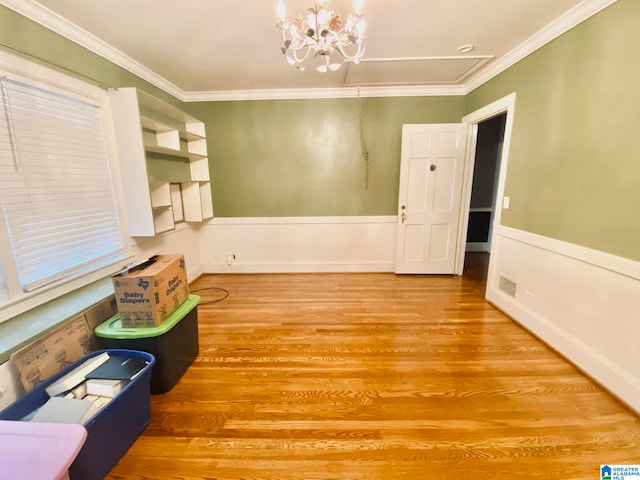 spare room featuring hardwood / wood-style floors, an inviting chandelier, and ornamental molding