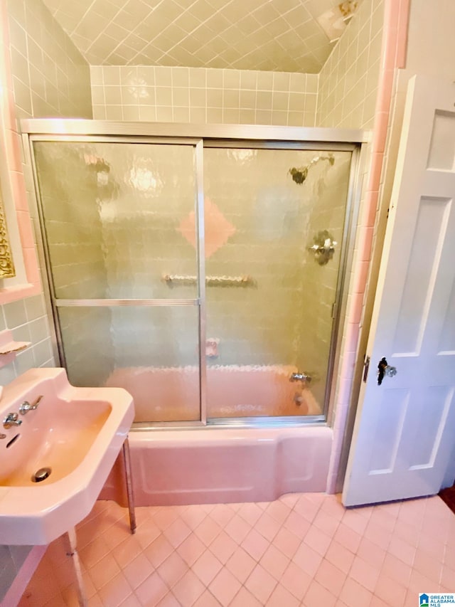 bathroom with tile walls, enclosed tub / shower combo, and tile patterned flooring