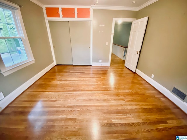 unfurnished bedroom with light wood-type flooring, a closet, and crown molding