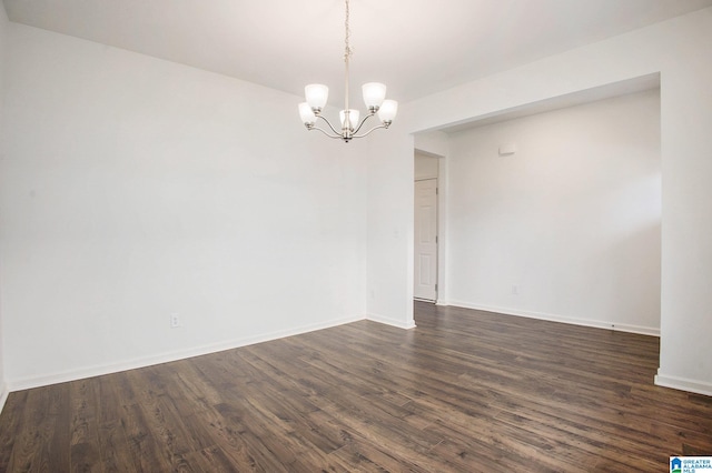 empty room featuring dark wood-type flooring and a notable chandelier