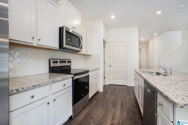 kitchen with appliances with stainless steel finishes, dark hardwood / wood-style floors, white cabinetry, and sink