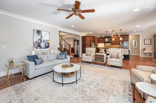 living room featuring light hardwood / wood-style floors, ornamental molding, and ceiling fan