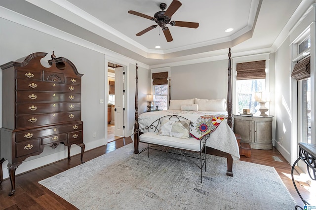 bedroom featuring a tray ceiling, ceiling fan, dark hardwood / wood-style floors, and ensuite bathroom