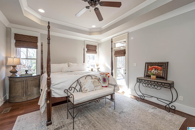 bedroom with ceiling fan, a raised ceiling, and hardwood / wood-style flooring