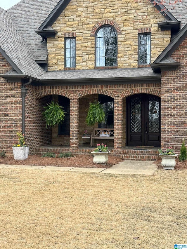 doorway to property featuring a yard, a porch, and french doors