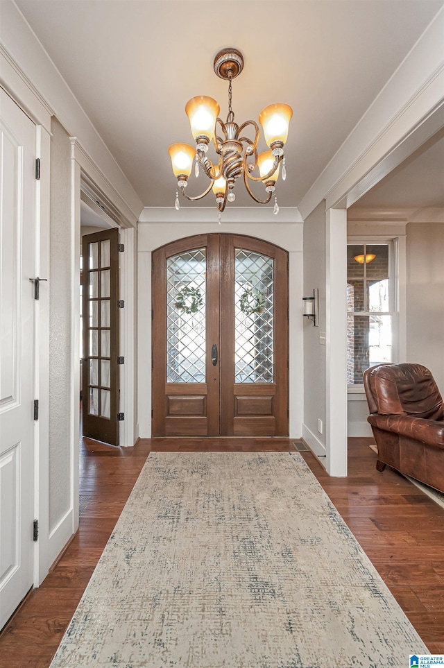 entrance foyer with a notable chandelier, dark hardwood / wood-style floors, and french doors