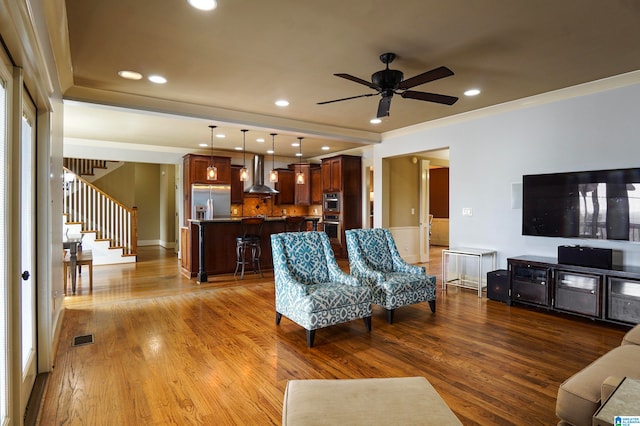 living room with light hardwood / wood-style floors, ceiling fan, and crown molding