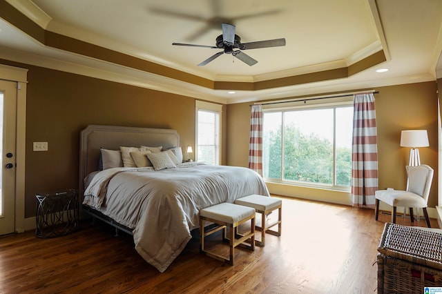 bedroom featuring ceiling fan, ornamental molding, dark wood-type flooring, and a tray ceiling