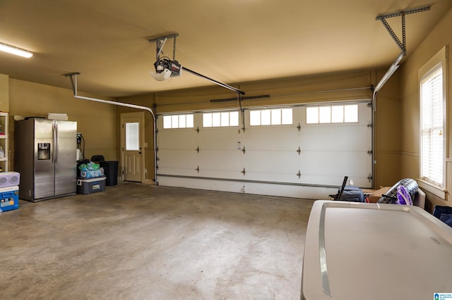 garage featuring stainless steel fridge with ice dispenser and a garage door opener