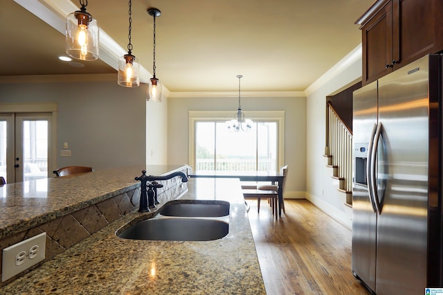 kitchen with stainless steel fridge with ice dispenser, sink, decorative light fixtures, dark stone countertops, and hardwood / wood-style floors