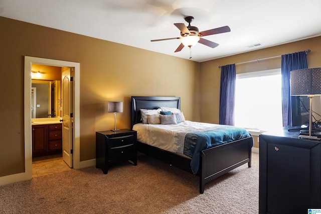 bedroom featuring light carpet, ensuite bath, and ceiling fan