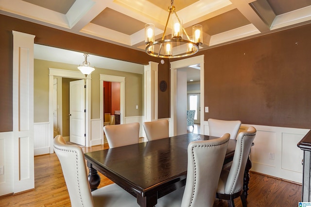 dining area featuring hardwood / wood-style flooring, beam ceiling, coffered ceiling, and an inviting chandelier