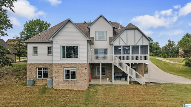 rear view of property with a lawn, a patio area, a sunroom, and central AC unit