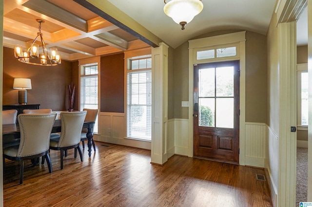 dining space with beamed ceiling, coffered ceiling, dark wood-type flooring, and a chandelier