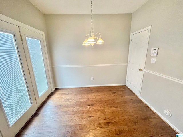 unfurnished dining area featuring hardwood / wood-style floors and a notable chandelier