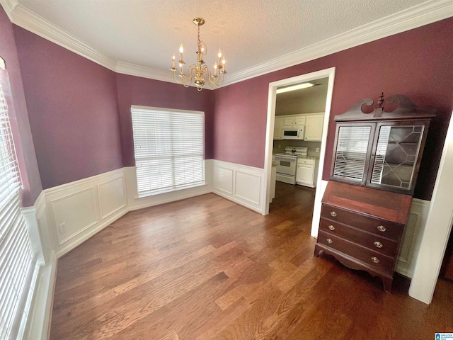 unfurnished dining area with ornamental molding, a textured ceiling, hardwood / wood-style floors, and an inviting chandelier