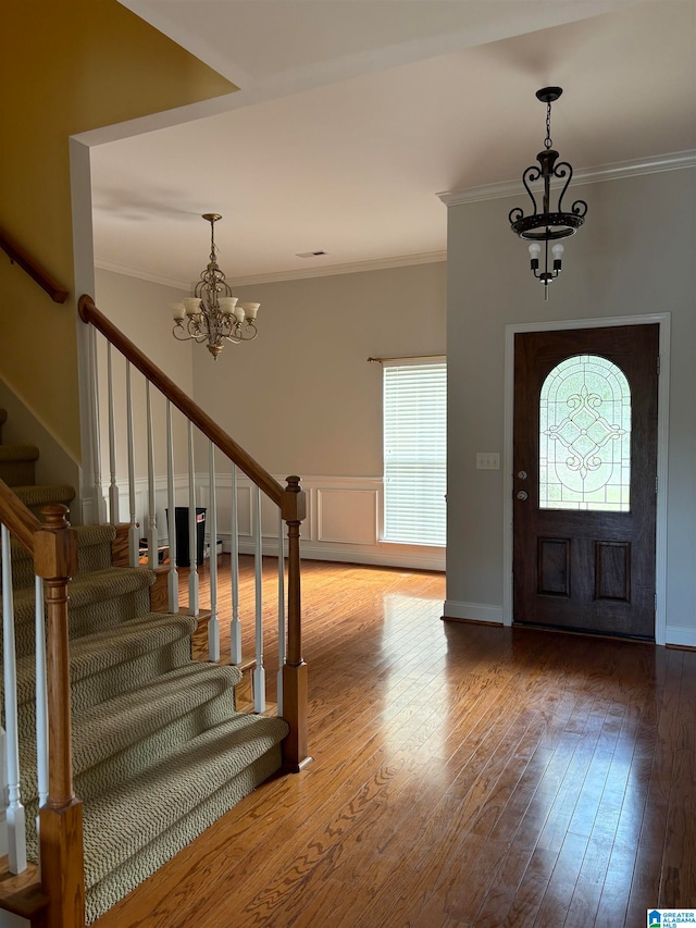 entryway featuring wood-type flooring, an inviting chandelier, and crown molding