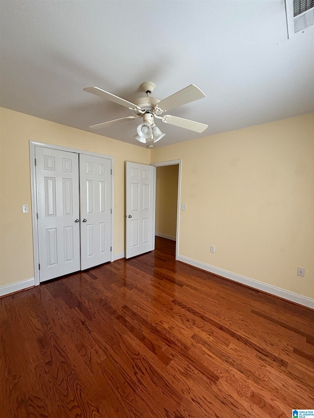 unfurnished bedroom featuring dark wood-type flooring, a closet, and ceiling fan