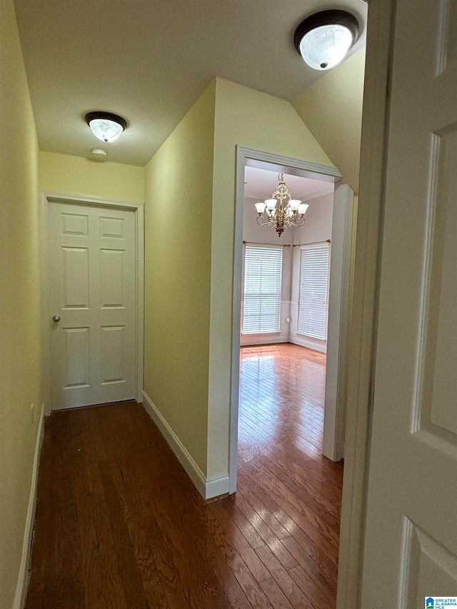 hall featuring dark wood-type flooring and an inviting chandelier