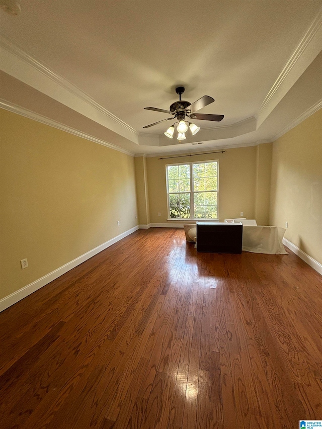 unfurnished living room with ornamental molding, a raised ceiling, ceiling fan, and dark hardwood / wood-style floors