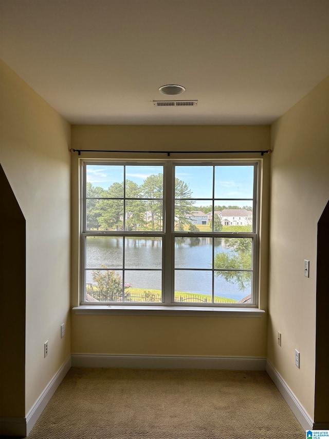 carpeted spare room featuring a water view