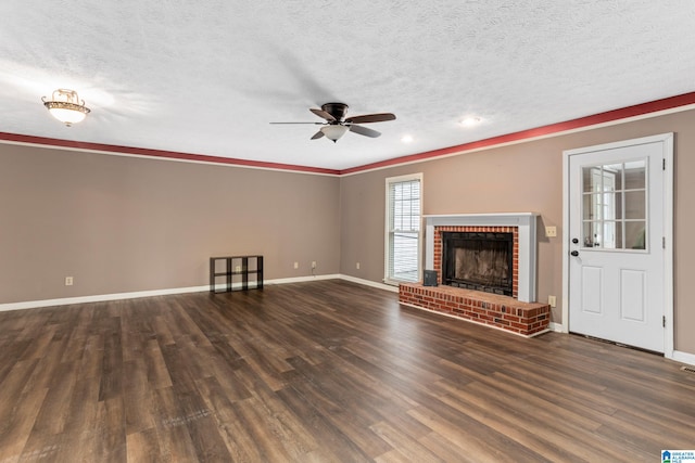 unfurnished living room with a textured ceiling, ceiling fan, a brick fireplace, and dark hardwood / wood-style flooring