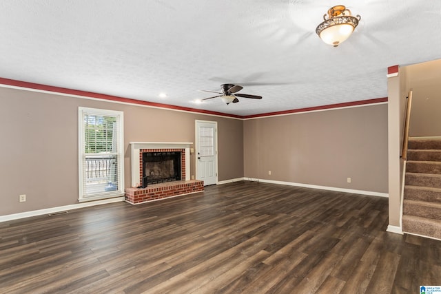 unfurnished living room with ornamental molding, a textured ceiling, a brick fireplace, ceiling fan, and dark hardwood / wood-style floors