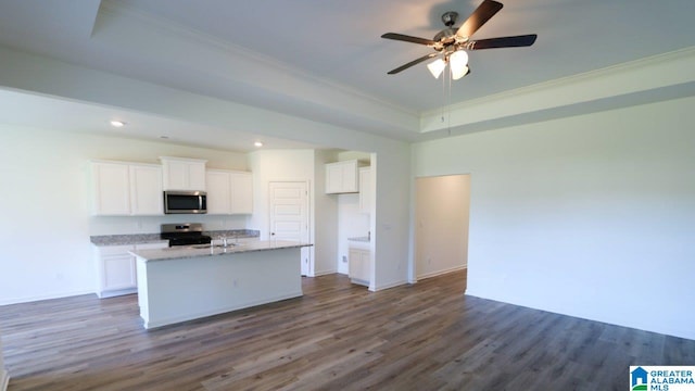 kitchen featuring dark wood-type flooring, appliances with stainless steel finishes, light stone counters, an island with sink, and white cabinets