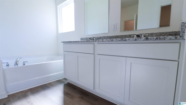 bathroom with hardwood / wood-style flooring, vanity, and a bathtub