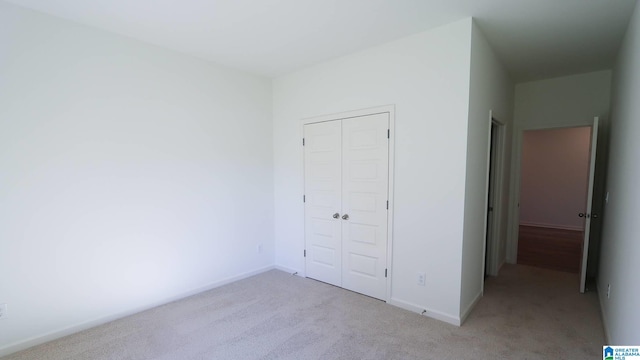 unfurnished bedroom with light colored carpet and a closet