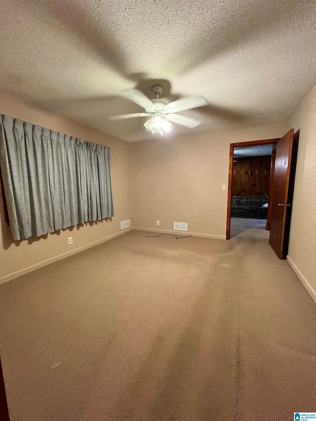 spare room with a textured ceiling, ceiling fan, and carpet flooring