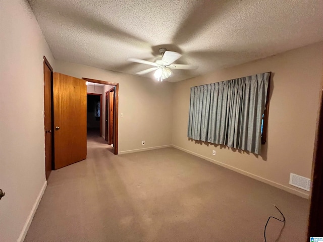 carpeted empty room with ceiling fan and a textured ceiling