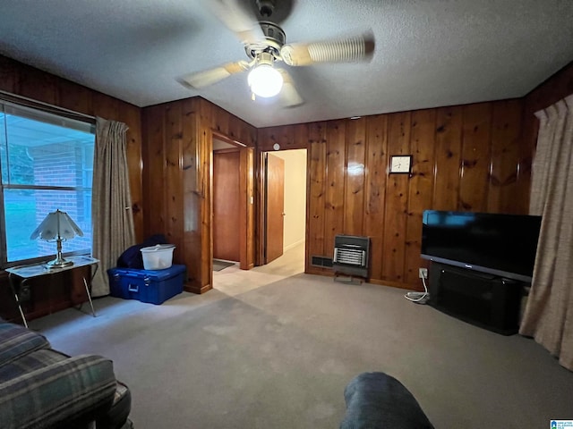 carpeted living room featuring a textured ceiling, ceiling fan, and wood walls