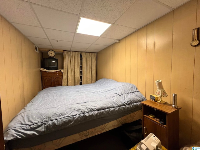 bedroom featuring wood walls and a drop ceiling