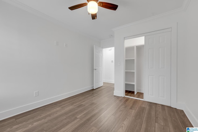 unfurnished bedroom with crown molding, wood-type flooring, ceiling fan, and a closet