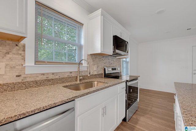 kitchen featuring stainless steel appliances, sink, white cabinets, and light hardwood / wood-style floors