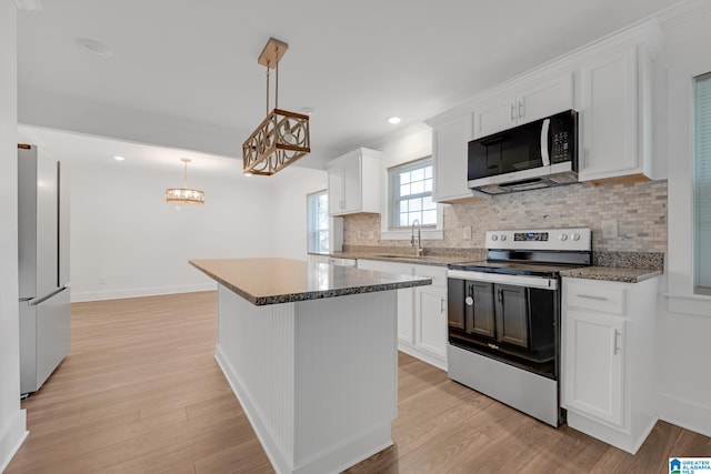 kitchen with light hardwood / wood-style flooring, appliances with stainless steel finishes, white cabinetry, sink, and a kitchen island