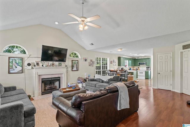 living room with ceiling fan, hardwood / wood-style floors, a premium fireplace, and a healthy amount of sunlight